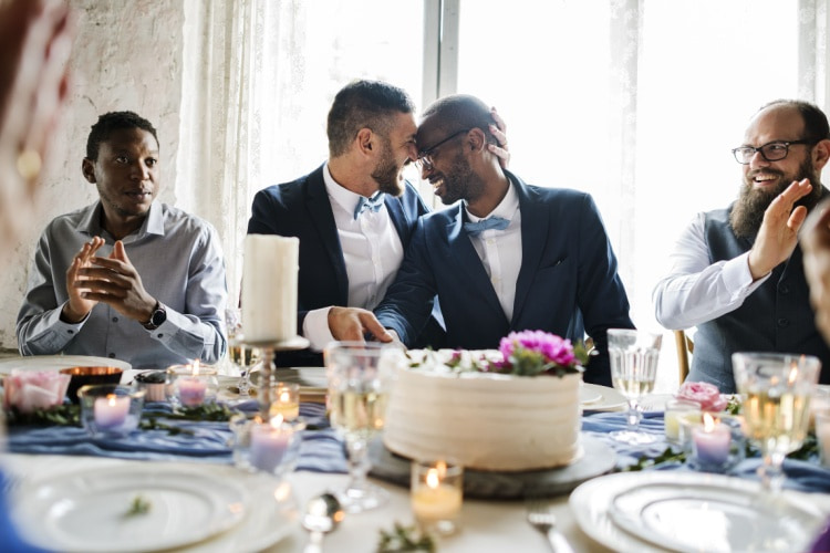 two grooms laughing together at their wedding reception