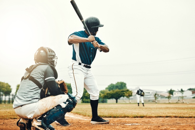 a batter steps up to the plate while the catcher kneels behind him